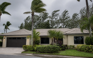 Impact-rated windows on a Florida home in Venice from a new window installation during hurricane season preparation, with palm trees and an overcast late-summer sky.